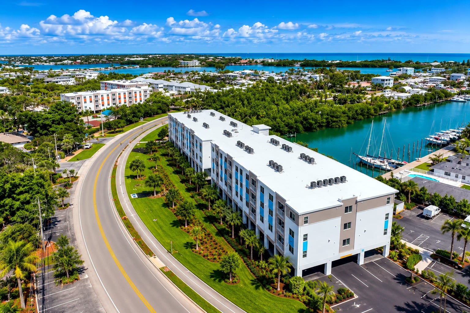 Daytime aerial of Coco Vista, the blue-panelled building in front of its orange-panelled twin, beside the marina