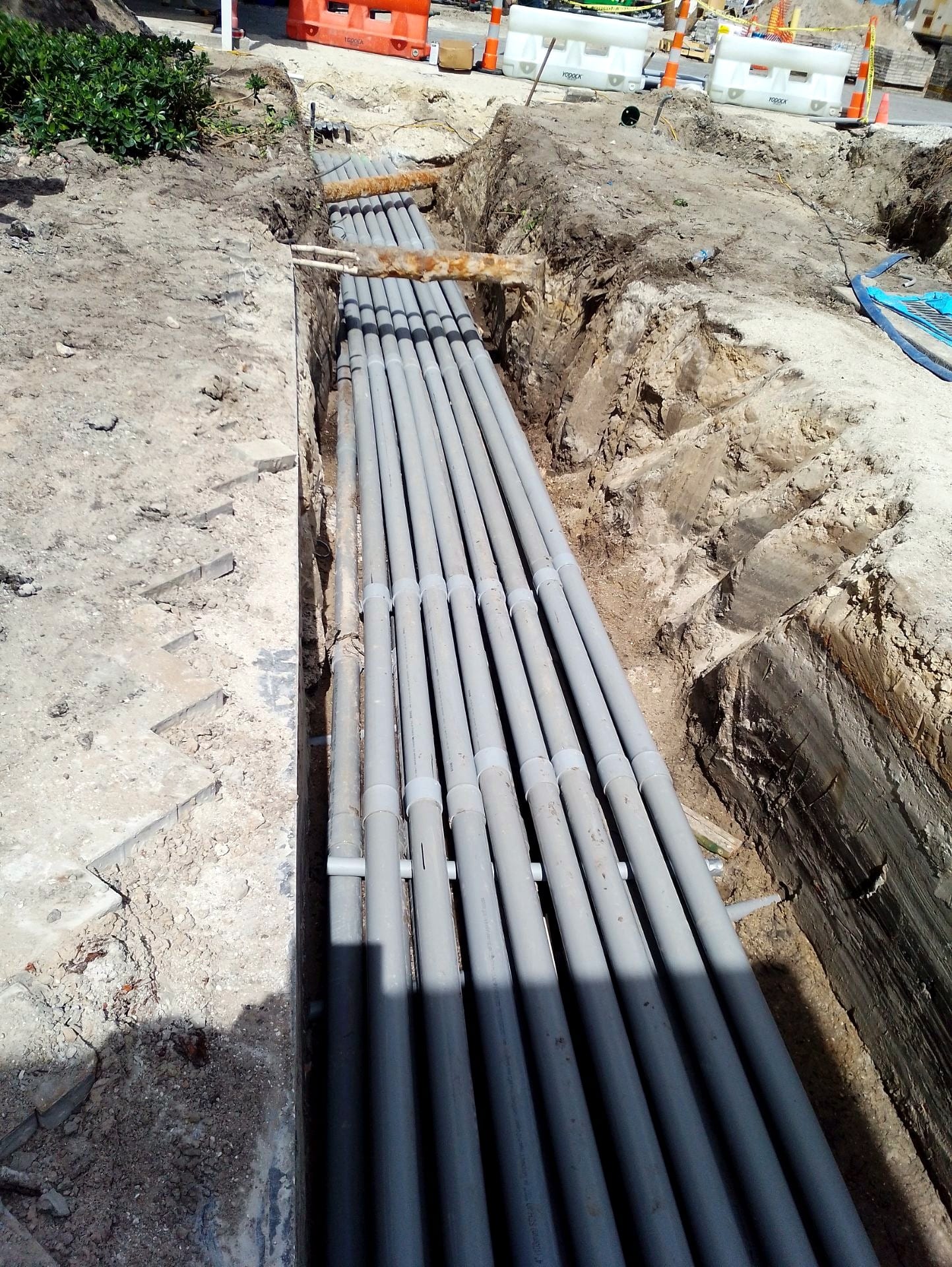 Duct bank conduits staged in an open trench alongside the building
