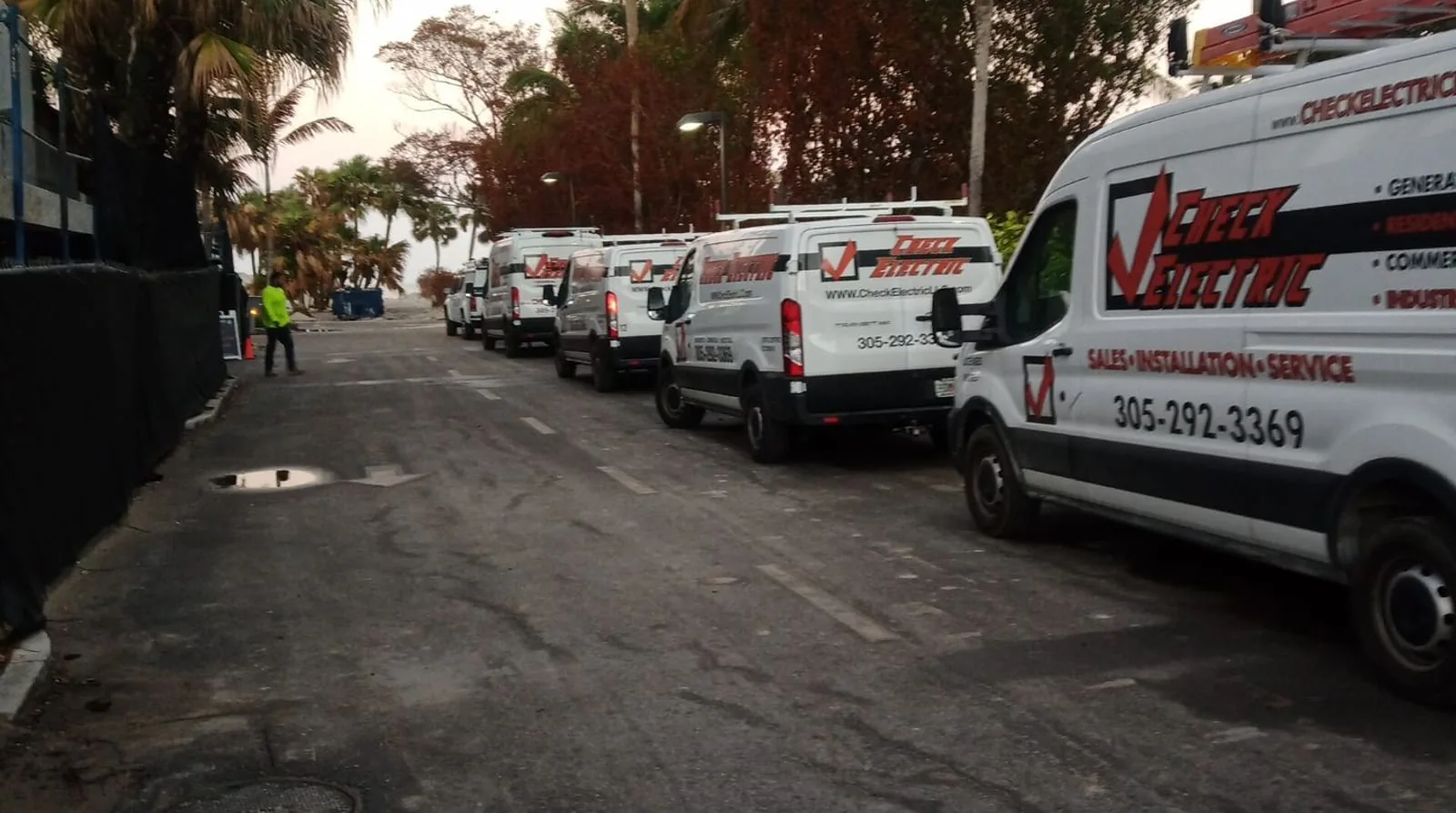 Check Electric service vans lined up along a Key West job site at dawn